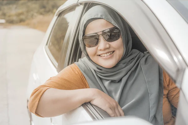 Portrait of Asian muslim lady smiling while drive her car, lifestyle having fun leisure in vacation trip, car ride sharing concept