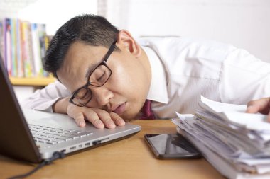 Asya işadamı için aşırı yorgun ve uyku önünde onun laptop ve paperworks ofis portre