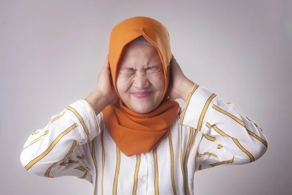Portrait of Asian muslim lady wearing hijab close hear ears with hands as if do not want to hear something bad