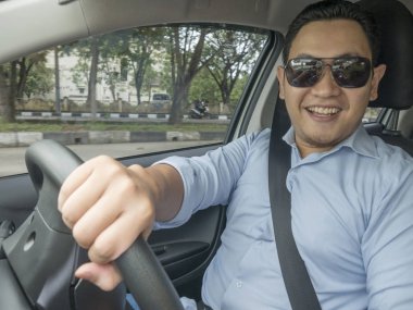 Gülümseyen ve sürme bir araba, iyi görünümlü girişimci, araba kavramı paylaşımı genç Asyalı adam portresi