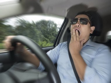 Hareket Bulanıklığı odak resim yung Asya erkek sürücü nedeniyle uykulu bir araba, tehlike trafik kaza sigortası kavramı, sürme sırasında yorgun esneme portresi Yakınlaştırılmış