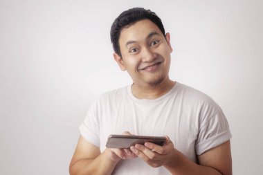 Fotoğraf resim portre sevimli yakışıklı genç Asyalı adamın komik surat tablet akıllı telefonda oyunlar oynamak ile