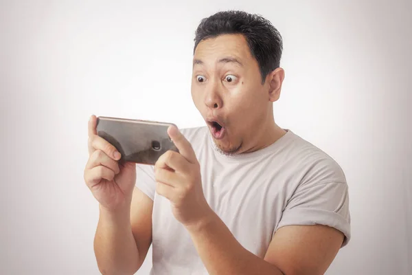 照片图像肖像一个可爱英俊的年轻亚洲男子与有趣的脸在平板电脑智能手机上玩游戏 — 图库照片