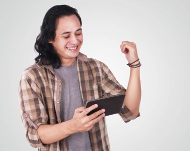 Sevimli yakışıklı bir genç Asyalı adam uzun saçlı ve komik surat tablete oyun portresi