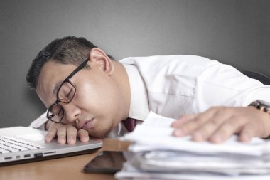 Asya işadamı için aşırı yorgun ve uyku önünde onun laptop ve paperworks ofis portre