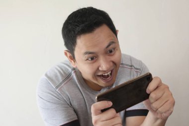 Komik genç Asyalı adam Tablet akıllı telefonda oyunlar oynamak