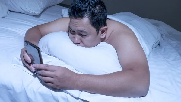 Conceito de viciado em telefone, homem asiático com telefone inteligente na cama — Fotografia de Stock