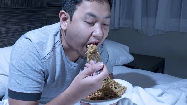 Jeść o północy, jedzenie złe przyzwyczajenia, późno kolację na łóżku — Zdjęcie stockowe