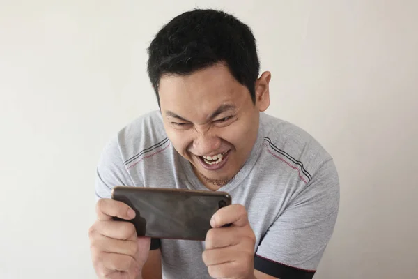 Lustige junge asiatische Kerl spielen Spiele auf Tablet-Smartphone — Stockfoto