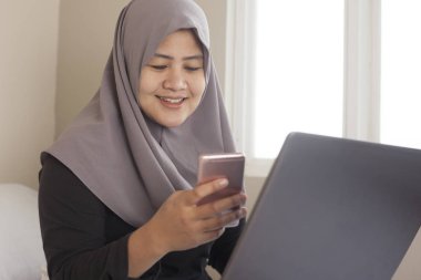 Dizüstü bilgisayar ve akıllı telefon onu çalışan mutlu Müslüman kadın olmak