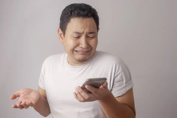 Junger Mann schreibt SMS, liest Chat auf seinem Handy und weint — Stockfoto