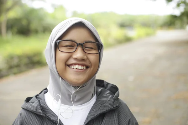 Menina muçulmana asiática feliz ouvindo música no parque — Fotografia de Stock