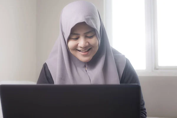 Yatak odasında dizüstü bilgisayar ile çalışan mutlu Müslüman kadın — Stok fotoğraf