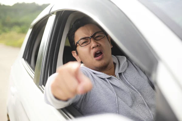 Enojado asiático conductor masculino, gritando señalando desde su coche —  Fotos de Stock