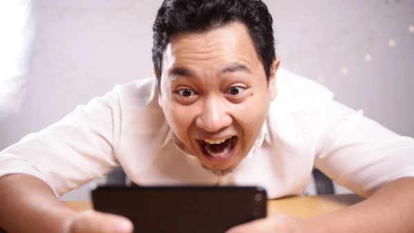 Grappige jonge Aziatisch vent spelen op Tablet-smartphone — Stockfoto