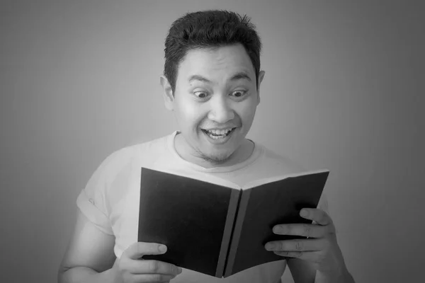 Joven leyendo libro con expresión feliz — Foto de Stock