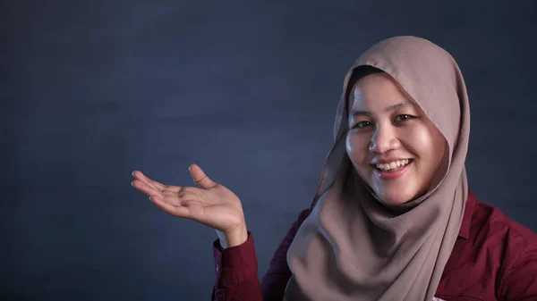 Muslimische Dame präsentiert etwas auf ihrer Seite mit Kopierraum — Stockfoto
