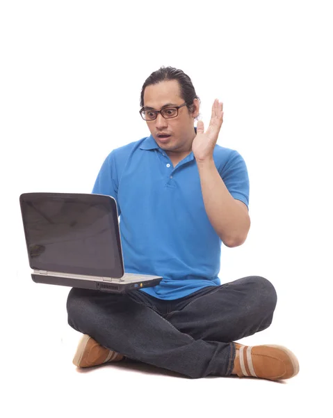 年轻人坐在地板上,在笔记本电脑上打字,震惊的手势 — 图库照片