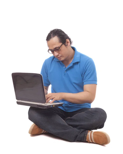 Mladý muž sedící na podlaze a přepisování v přenosném počítači — Stock fotografie