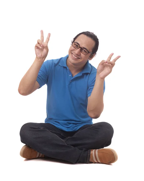 Χαριτωμένο αστείο Ασιάτης/ισσα άνθρωπος κάθομαι κάτω στο πάτωμα και εμφάνιση σύμβολο ειρήνης — Φωτογραφία Αρχείου