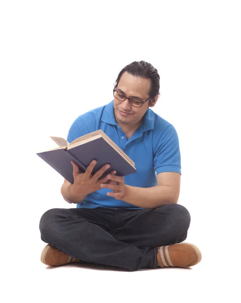 Junger Mann sitzt auf dem Boden und liest ein Buch — Stockfoto