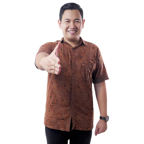 Joven asiático hombre usando batik camisa oferta apretón de manos gesto — Foto de Stock