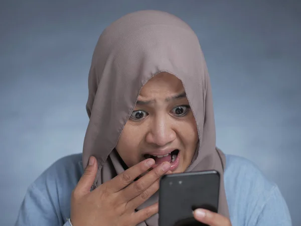 Mujer musulmana joven conmocionada expresión, mirando su teléfono —  Fotos de Stock