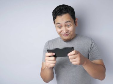 Komik genç Asyalı adam Tablet akıllı telefonda oyunlar oynamak