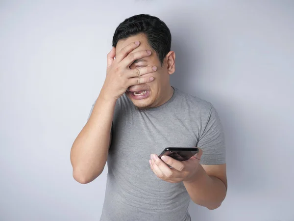 Junger Mann schreibt SMS, liest Chat auf seinem Handy und weint — Stockfoto