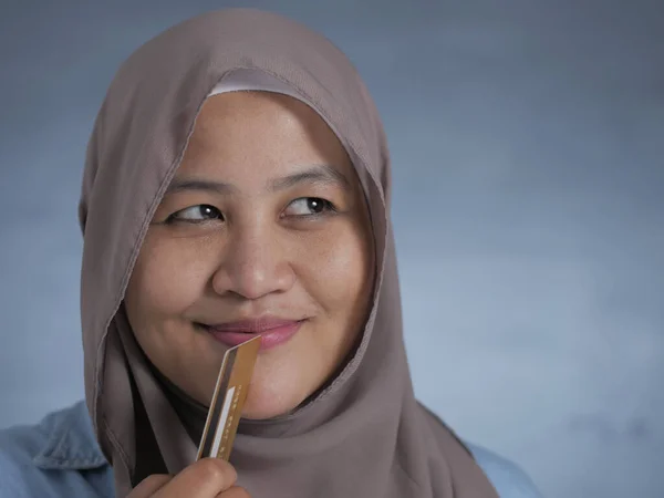 Мусульманка улыбается, держа кредитную карту — стоковое фото