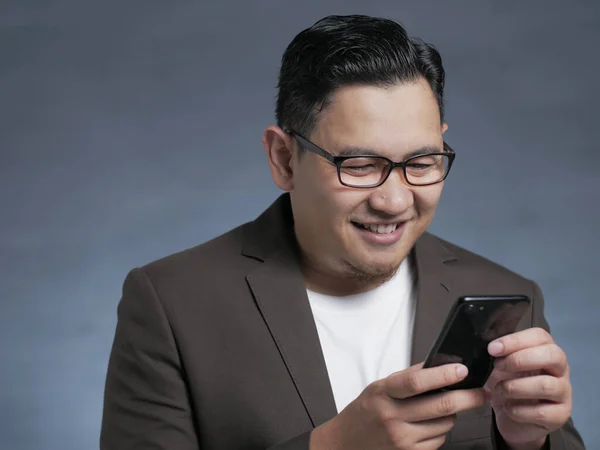 Joven Mensajes de texto de lectura de chat en su teléfono, sonriendo feliz — Foto de Stock