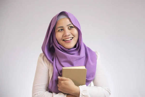 Muzułmanka trzyma książkę, myślenie i uśmiech — Zdjęcie stockowe