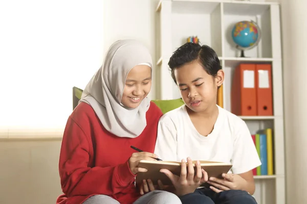 孩子们一起学习 穆斯林姐姐带着头巾帮助或教她的弟弟做家务 教育和快乐的家庭观念 — 图库照片