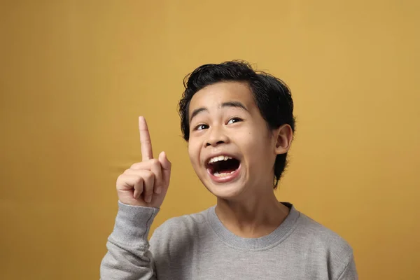 聪明的亚洲男孩穿着灰色的衬衫 面带微笑地抬起头 对着黄色背景 笑着有好主意的姿势 — 图库照片