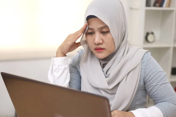 Asian muslim woman sad and frustrated to see her business report on laptop, businesswoman failure concept
