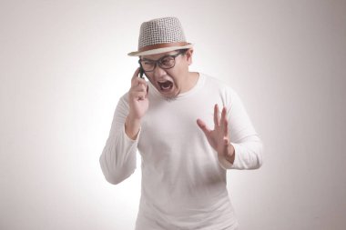 Çekici Asyalı genç adam telefonuyla konuşuyor, kötü haberler alıyor, şok olmuş kızgın bir jest yapıyor.