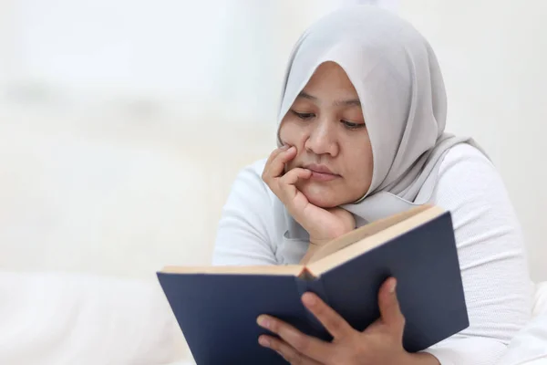 Glückliche Asiatische Muslimin Lächelt Während Sie Buch Auf Dem Bett — Stockfoto