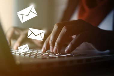 Ofiste dizüstü bilgisayarda yazan ve e-posta simgeleri yollanan Müslüman bir kadın. İletişim işi teknolojisi. Resmi seçici odak ile kapat