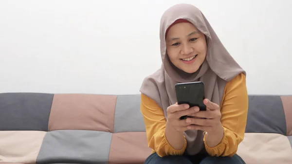 Wanita Muslim Asia Yang Cantik Menggunakan Telepon Sambil Duduk Sofa — Stok Foto