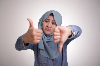 Asyalı Müslüman kadının portresi, iyi ve kötü karar kavramı olan iyi ve kötü bir jest gösteriyor.