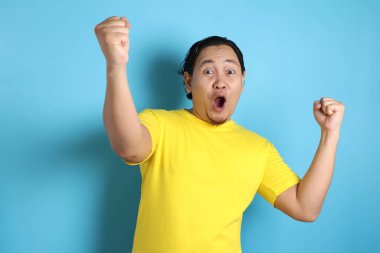 Gülümseyen ve ne mutlu ki, başarı jest kazanan iyi haber zaferini kutluyor ifade neşeli dans komik genç bir Asyalı adam portresi