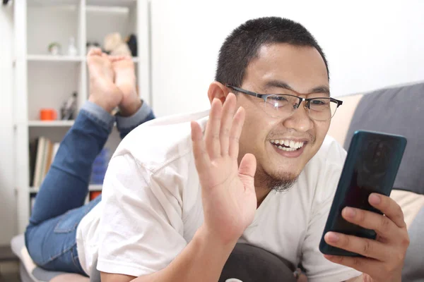 Азіатський Чоловік Робить Вдома Відеодзвінок Усміхаючись Камери Розмахуючи Нею Щасливий — стокове фото