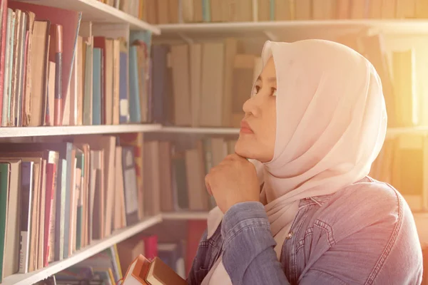 선택하고 책꽂이에서 선택하고 개념을 선택하고 도서관에서 공부하기를 생각하는 아시아 사실계 — 스톡 사진