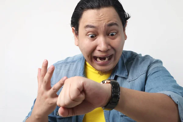Young Asian man worried by time when looking at his wristwatch. Work or school time deadline