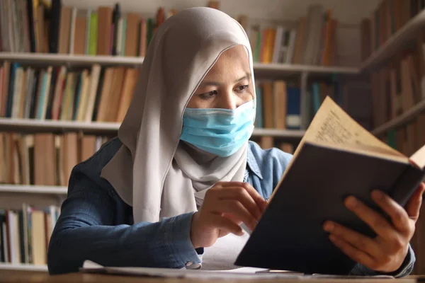 코로나 바이러스가 유행하는 도서관에서 책읽기를 배우고 이슬람 보안경을 — 스톡 사진