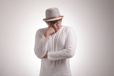 Asyalı genç bir adam, beyaz arka planda hayal kırıklığına uğramış bir jest, yarım vücut portresi gösteriyor.