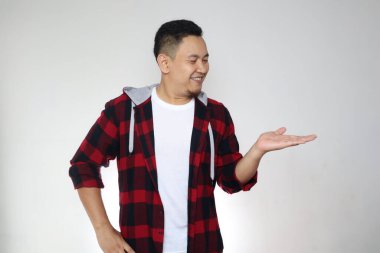 Genç Asyalı adam boş elle gülümseyerek bir şey gösteriyor. Kopya alanı ile pazarlama reklam portresi