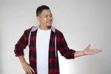 Mutlu, genç Asyalı adam gülümsüyor ve beyaz arka planda fotokopi alanı olan bir şeyi kendi tarafına çekiyor.