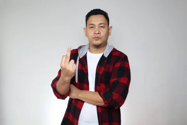 Portrait of angry Asian man shows middle finger rude gesture, looking at camera