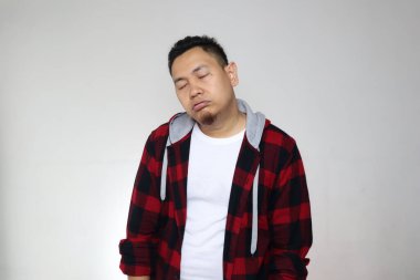 Uykulu, yorgun, komik, Asyalı bir adam uyurken gri arka planda yarı vücut portresi çiziyor.